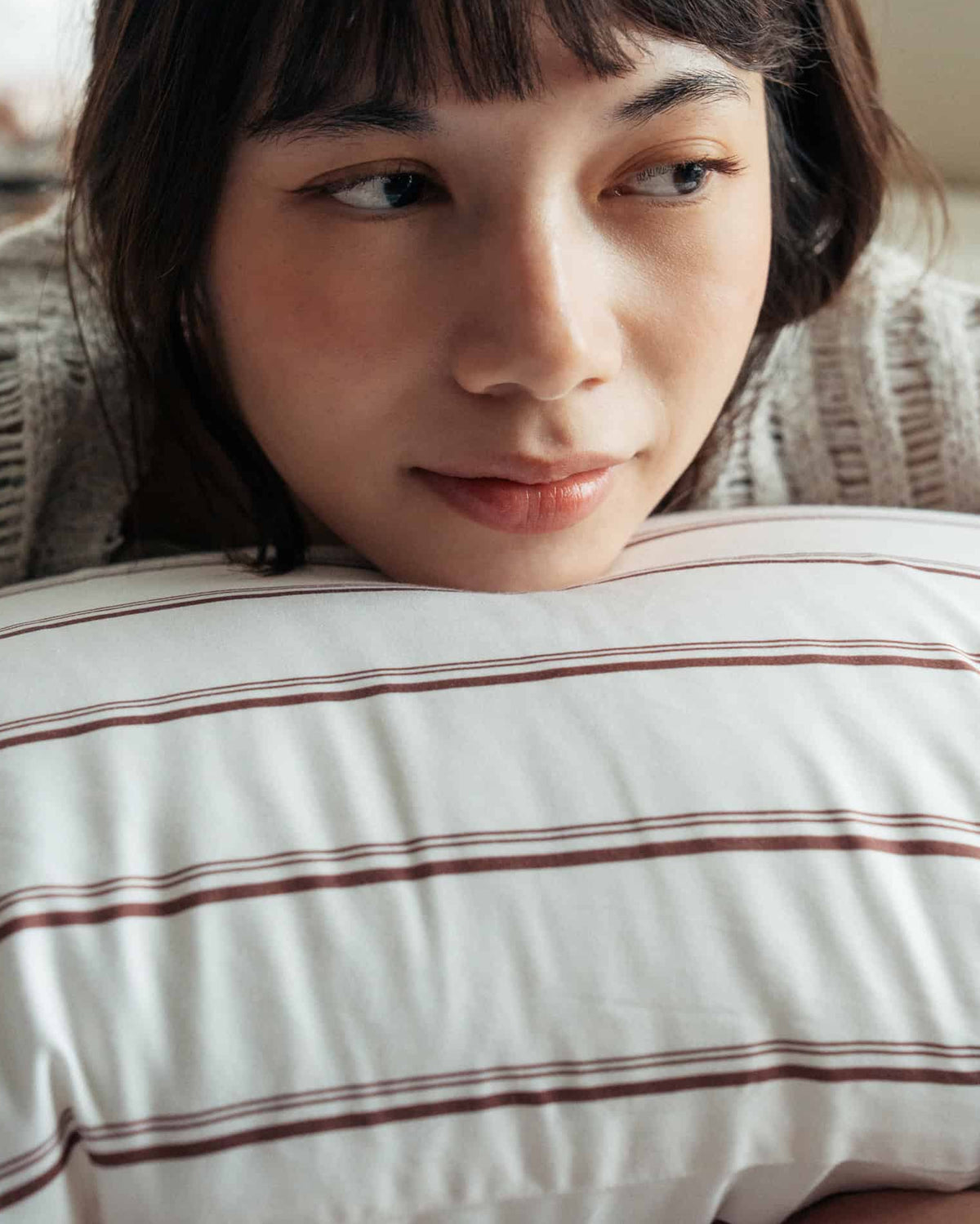 Woman lying on a striped pillow with a neutral expression